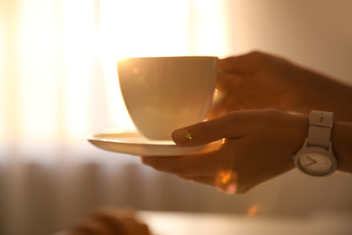 Photo of Woman holding cup of drink on blurred background, closeup. Lazy morning