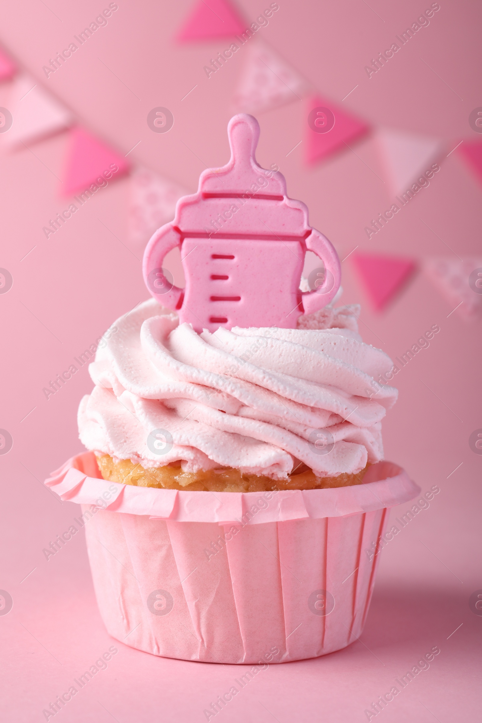 Photo of Beautifully decorated baby shower cupcake for girl with cream and topper on pink background