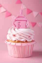 Photo of Beautifully decorated baby shower cupcake for girl with cream and topper on pink background