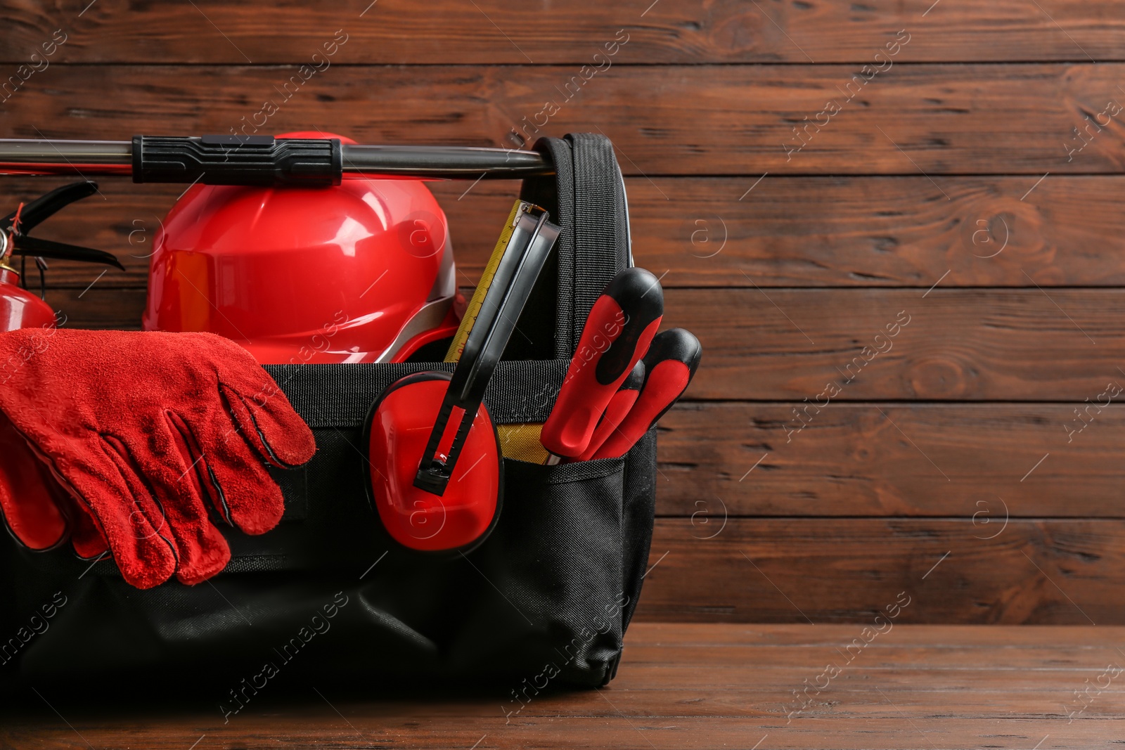 Photo of Black bag with construction tools on table against wooden background, space for text