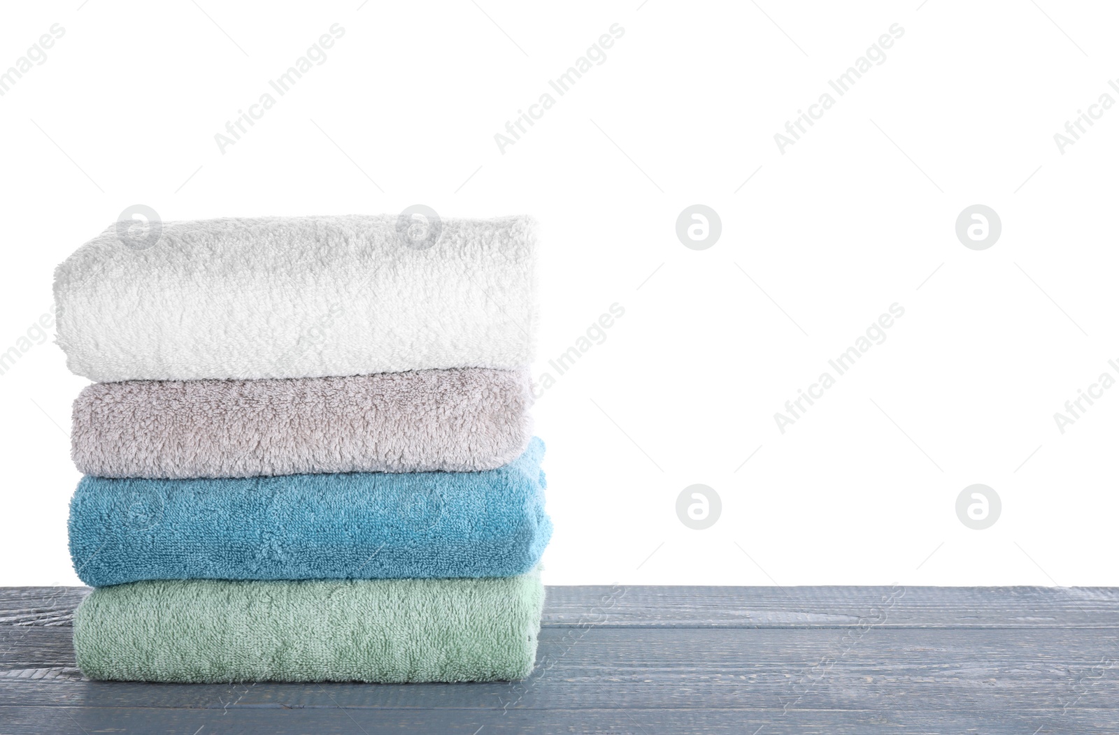 Photo of Fresh towels on grey wooden table against white background. Space for text