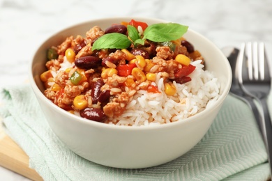 Photo of Tasty chili con carne served with rice in bowl on table