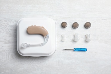 Photo of Flat lay composition with hearing aid and accessories on table