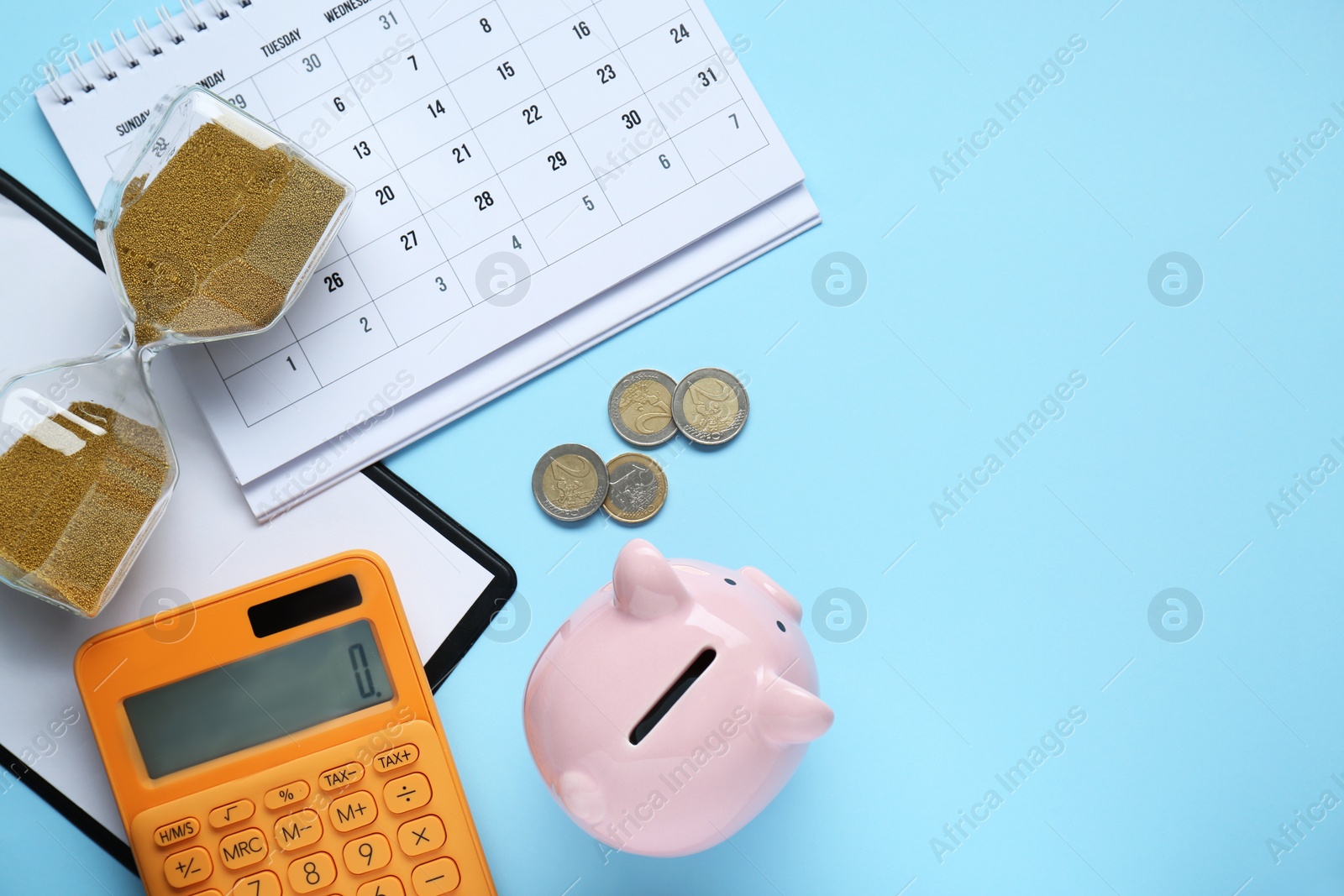 Photo of Flat lay composition with piggy bank and calculator on light blue background. Space for text