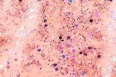 Photo of Shiny glitter on light pink background, top view