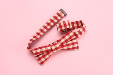 Photo of Stylish red and white gingham bow tie on pink background, top view