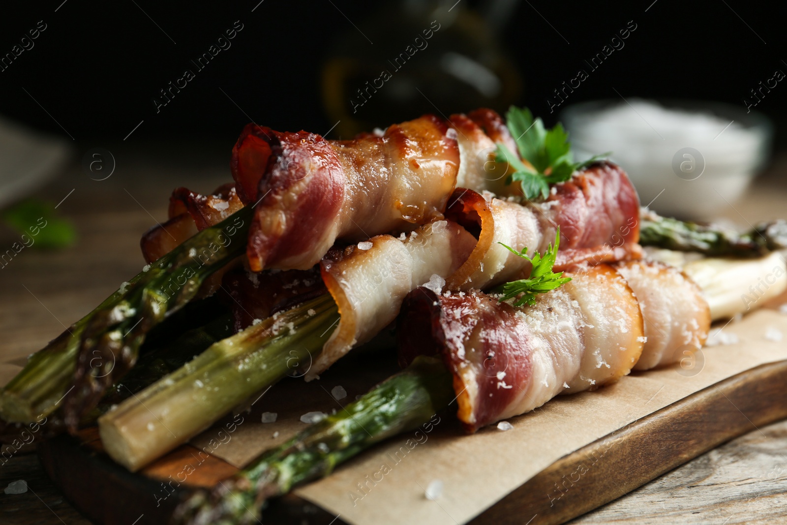 Photo of Oven baked asparagus wrapped with bacon on wooden board, closeup