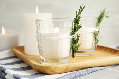 Wooden tray with burning candles on table