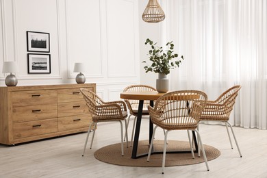 Photo of Dining room interior with comfortable furniture and eucalyptus branches