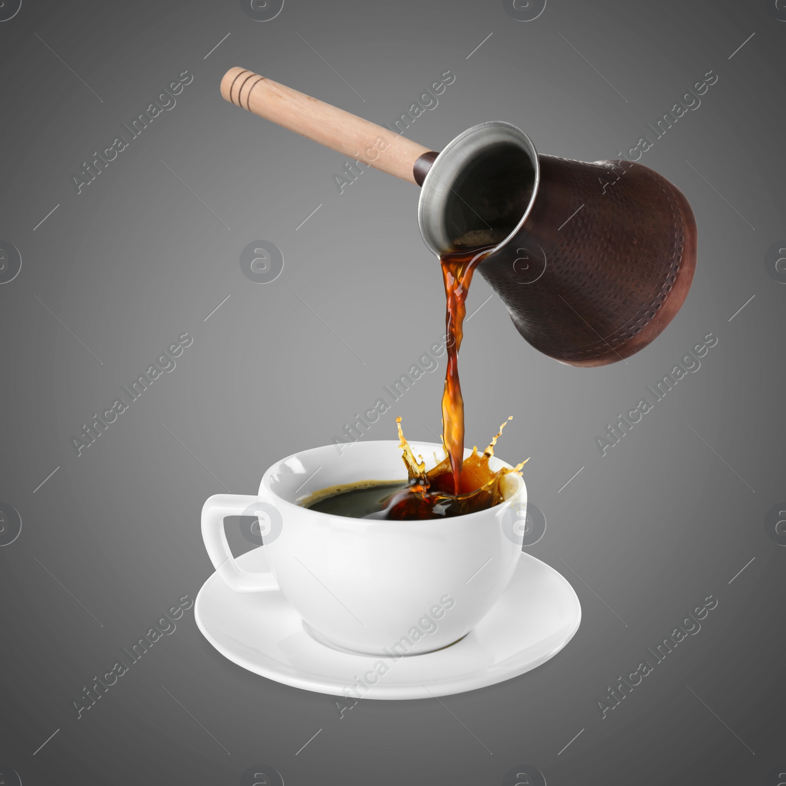 Image of Pouring freshly brewed aromatic coffee from turkish pot into cup. Objects in air on grey background