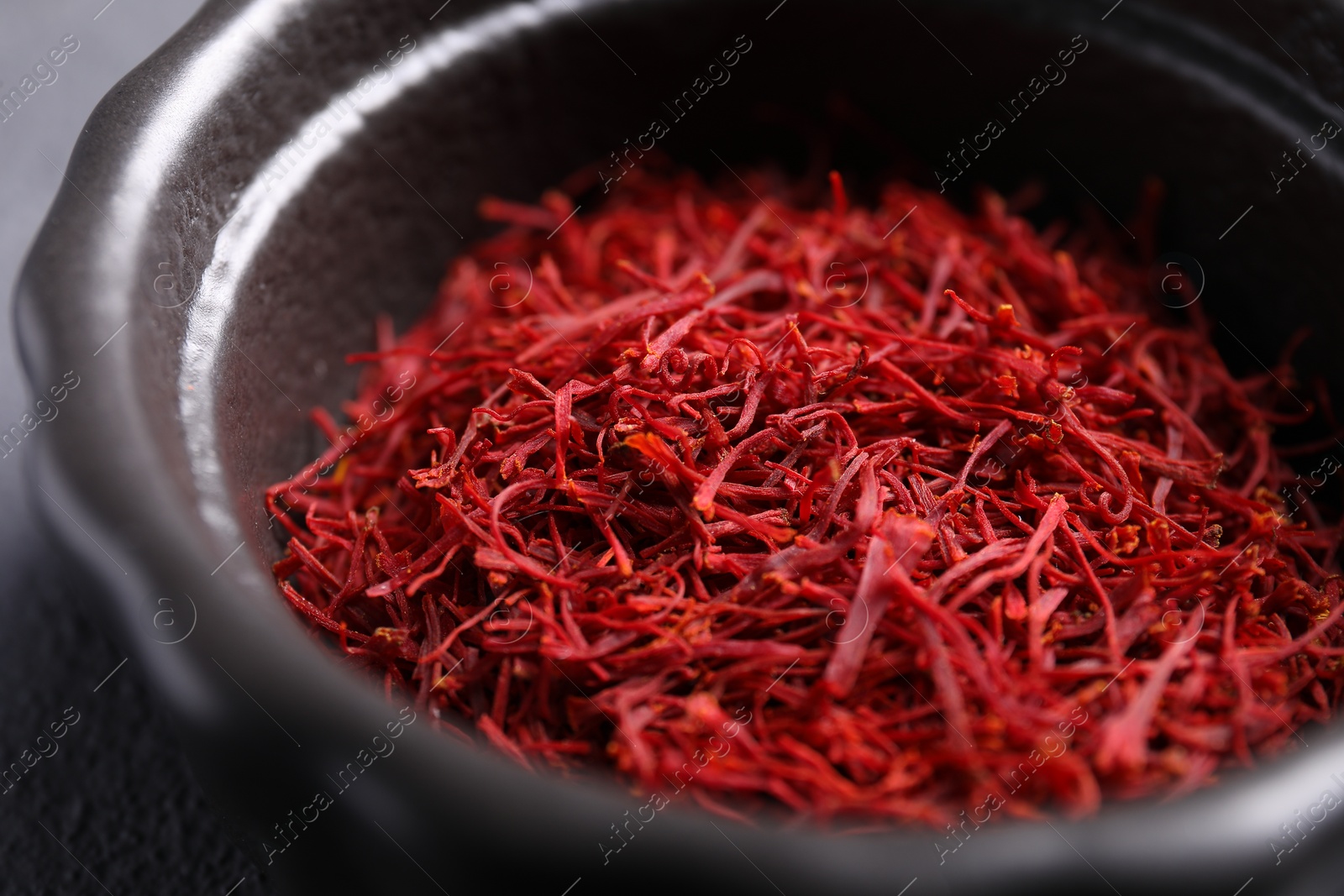 Photo of Aromatic saffron in bowl on table, closeup