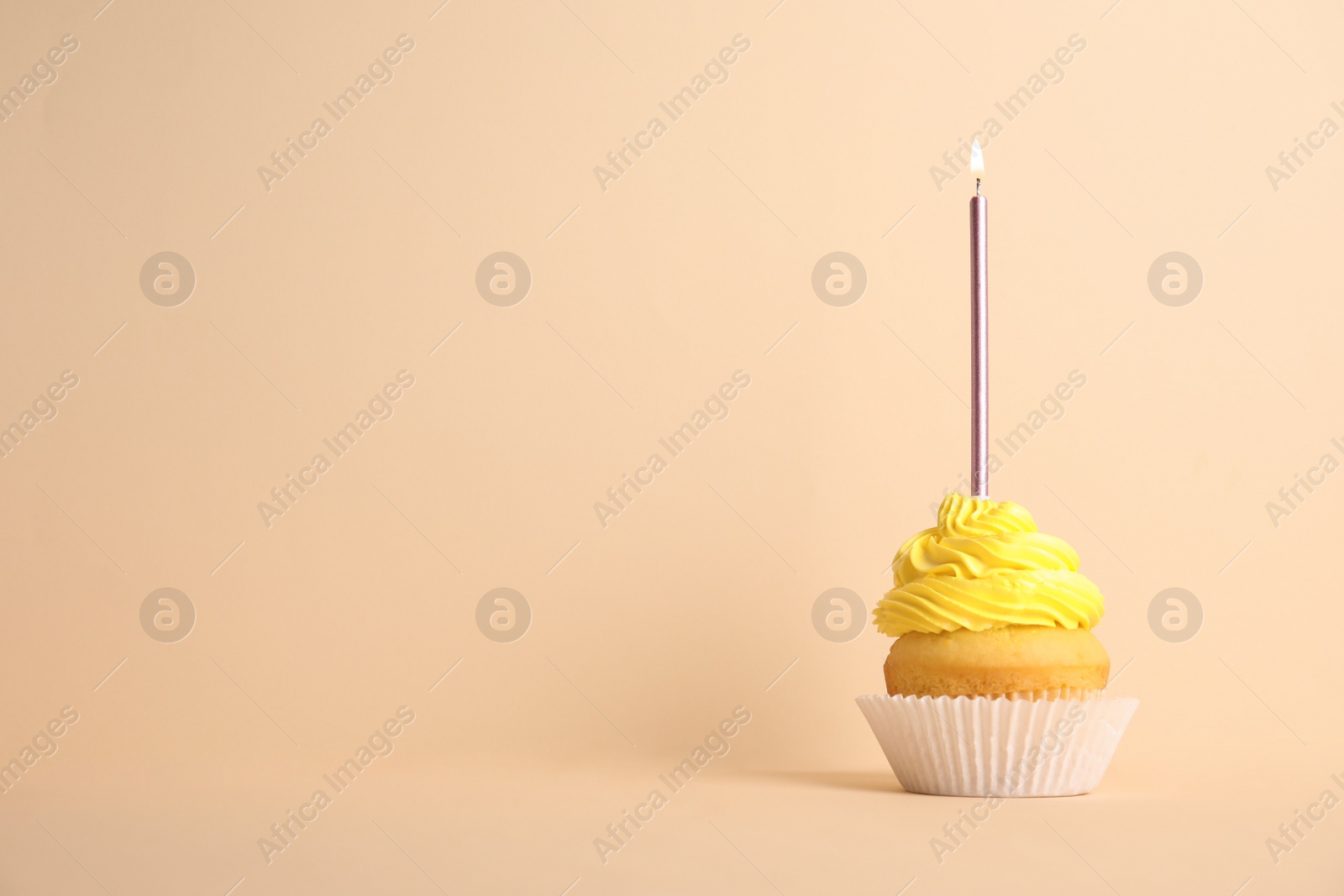 Photo of Birthday cupcake with candle on beige background, space for text