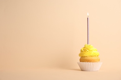 Photo of Birthday cupcake with candle on beige background, space for text