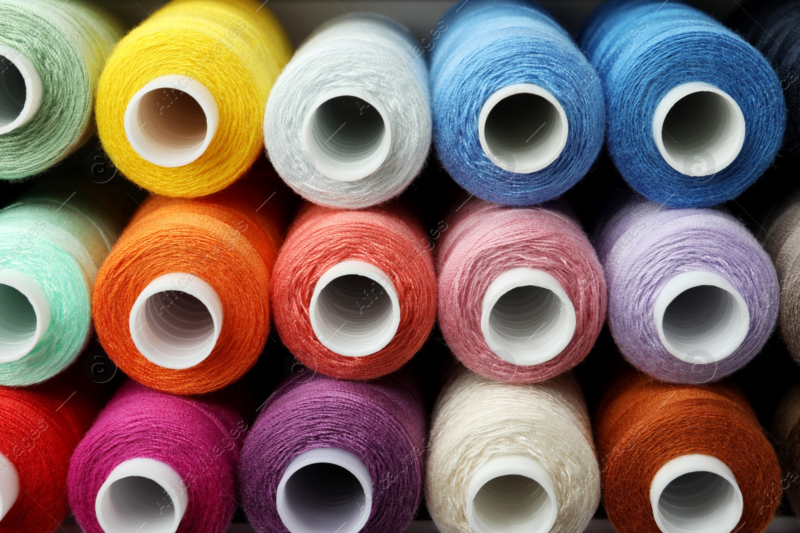 Photo of Set of different colorful sewing threads as background, above view