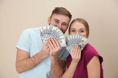 Photo of Happy young couple with money on color background
