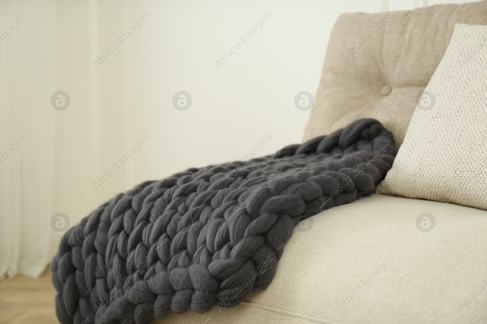 Photo of Knitted merino wool plaid on sofa in room