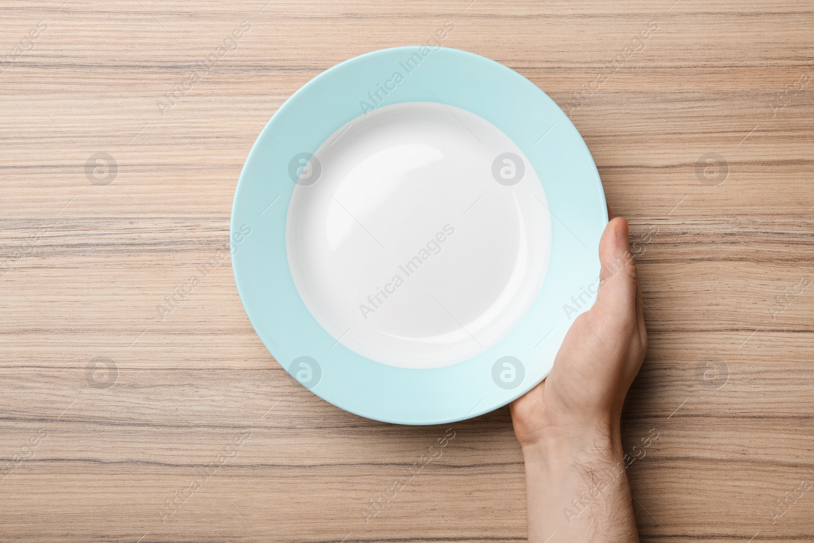 Photo of Man with empty plate at wooden table, top view