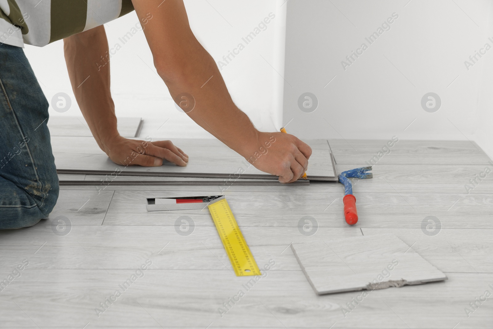 Photo of Professional worker installing new laminate flooring indoors, closeup