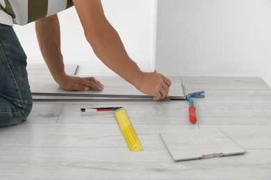 Photo of Professional worker installing new laminate flooring indoors, closeup