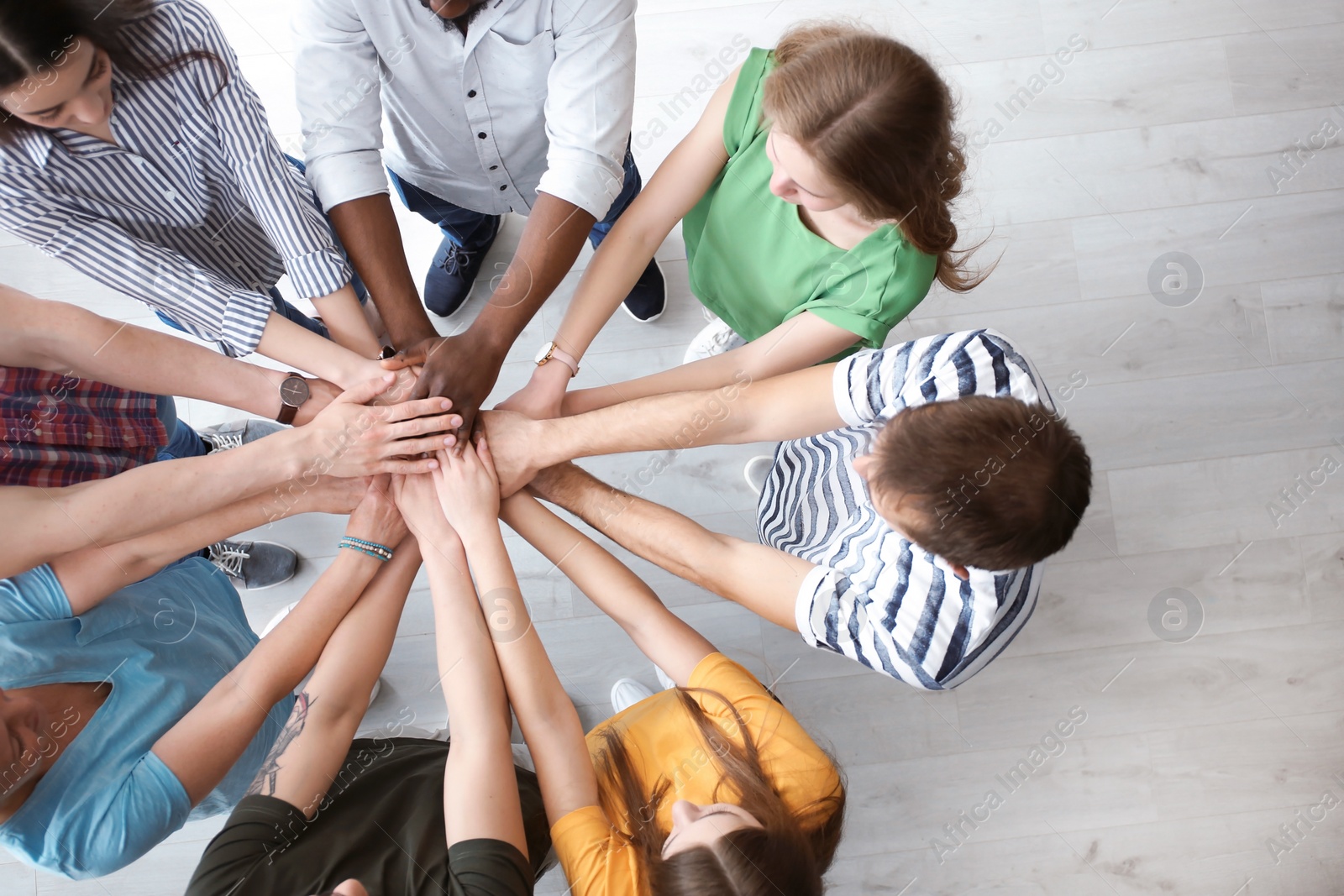 Photo of People putting hands together indoors. Unity concept