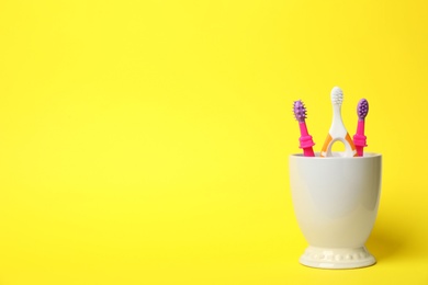 Photo of Baby toothbrushes in holder and space for text on color background