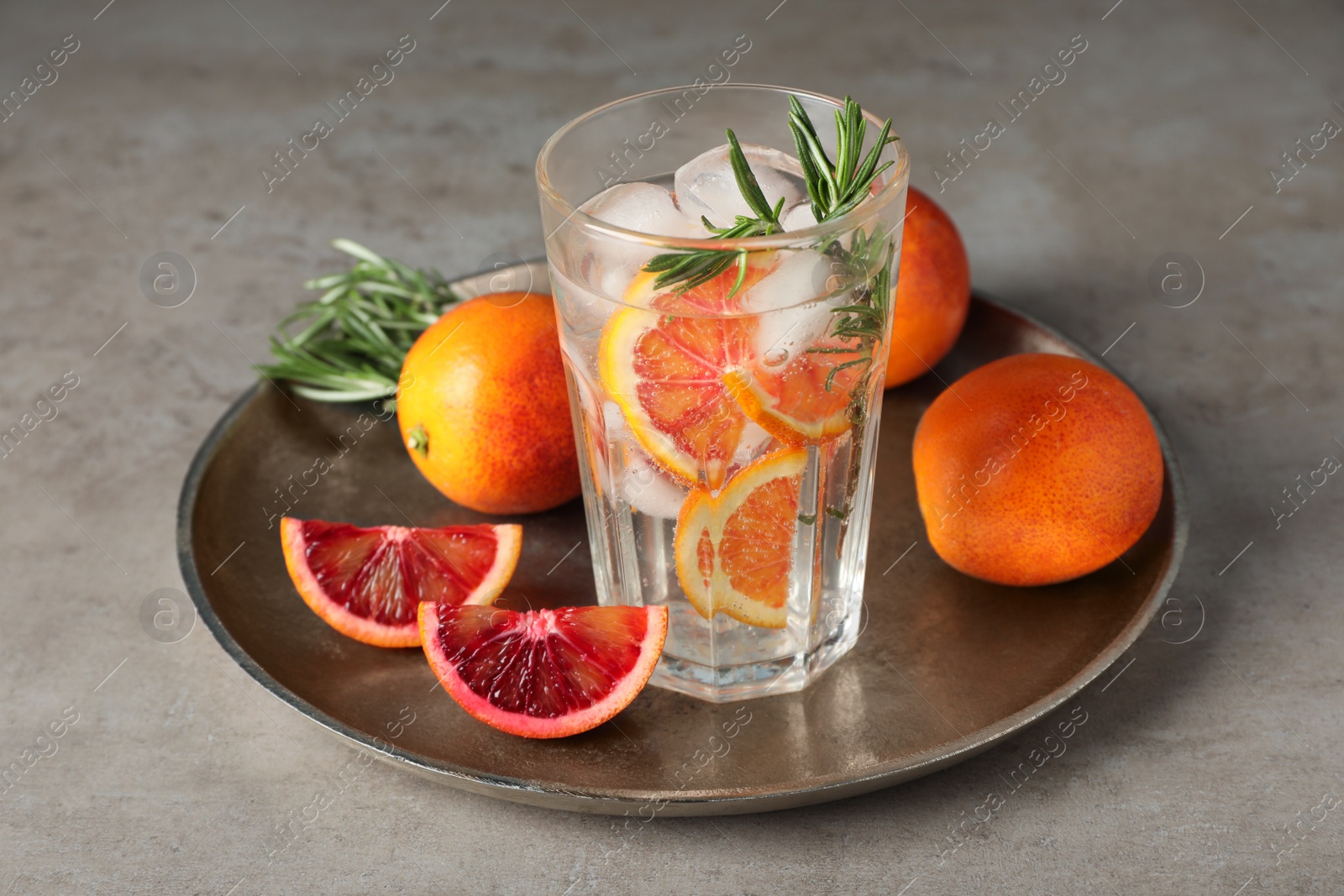 Photo of Delicious refreshing drink with sicilian orange and rosemary near fresh ingredients on grey table