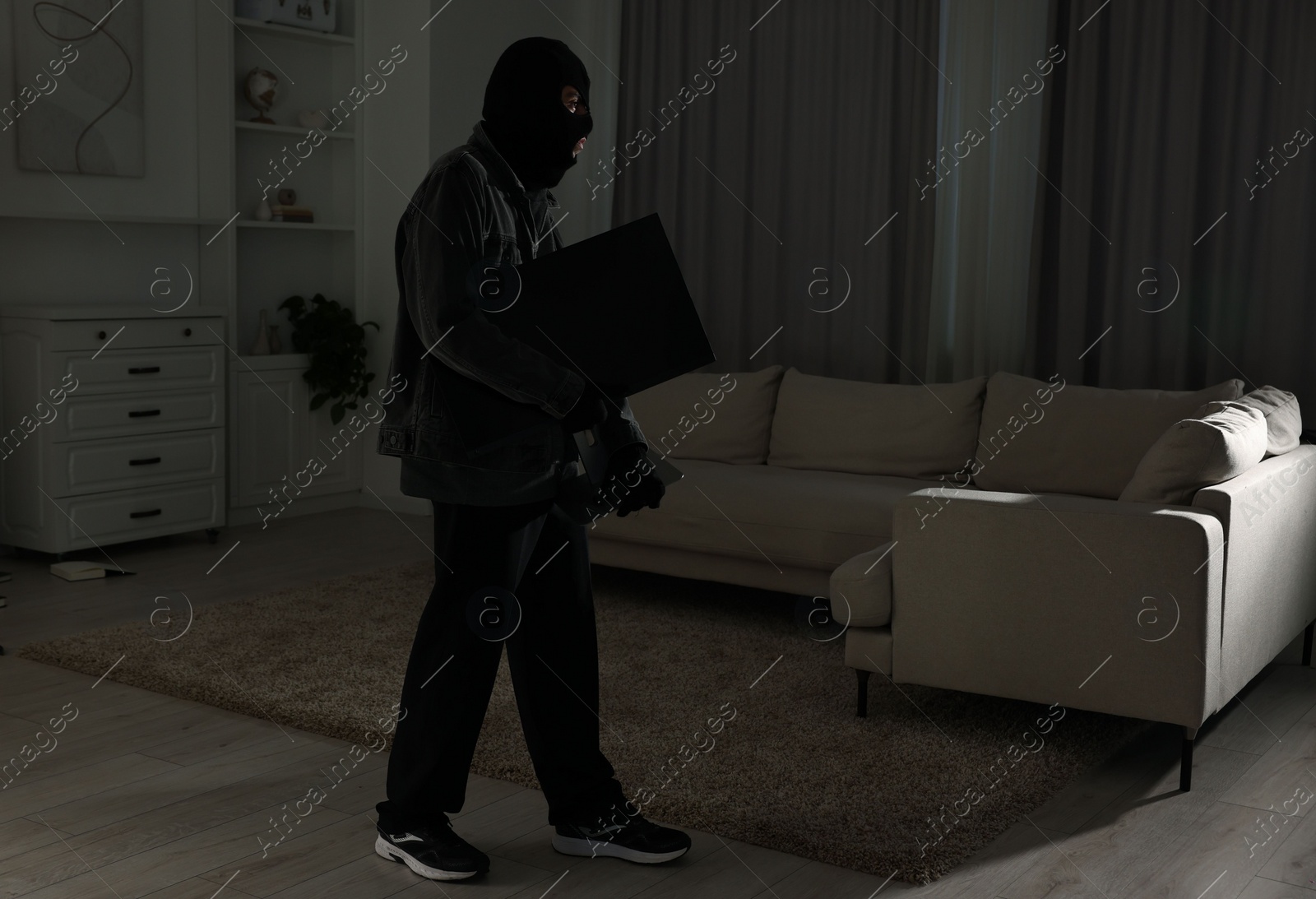 Photo of Thief stealing computer monitor at foreign house. Burglary