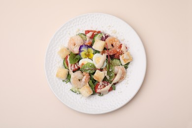 Photo of Delicious Caesar salad with shrimps on beige background, top view