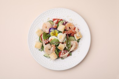 Delicious Caesar salad with shrimps on beige background, top view