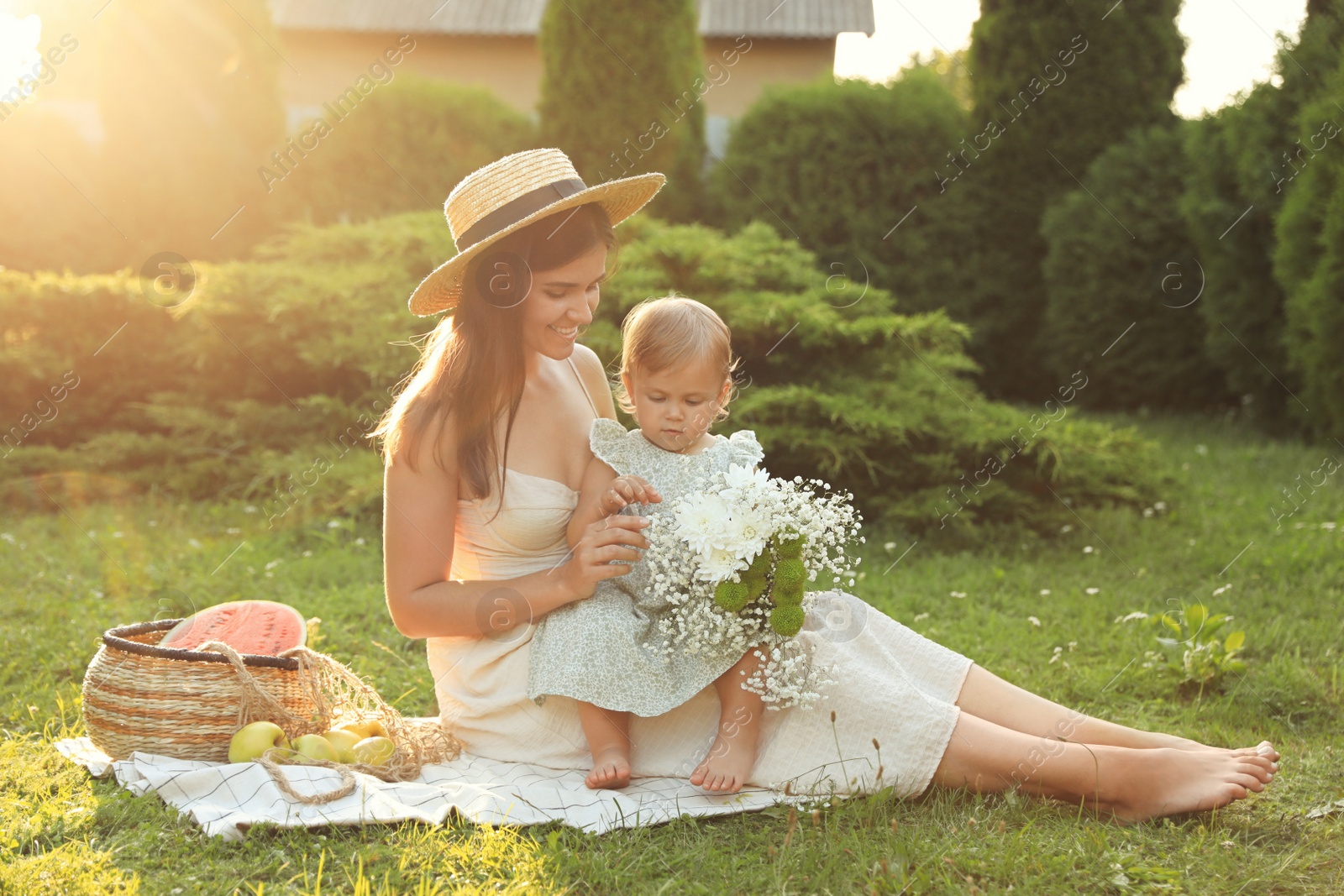 Photo of Mother with her baby daughter having picnic in garden on sunny day