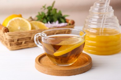 Cup of delicious tea with lemon and honey on white table