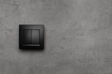 Photo of Black light switch on grey background. Space for text