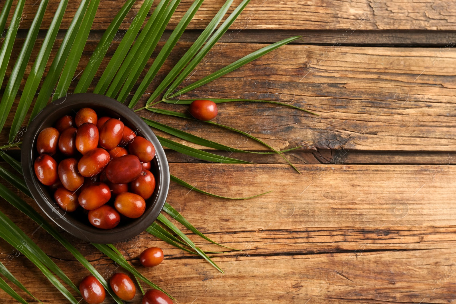 Photo of Palm oil fruits in bowl on wooden table, flat lay. Space for text