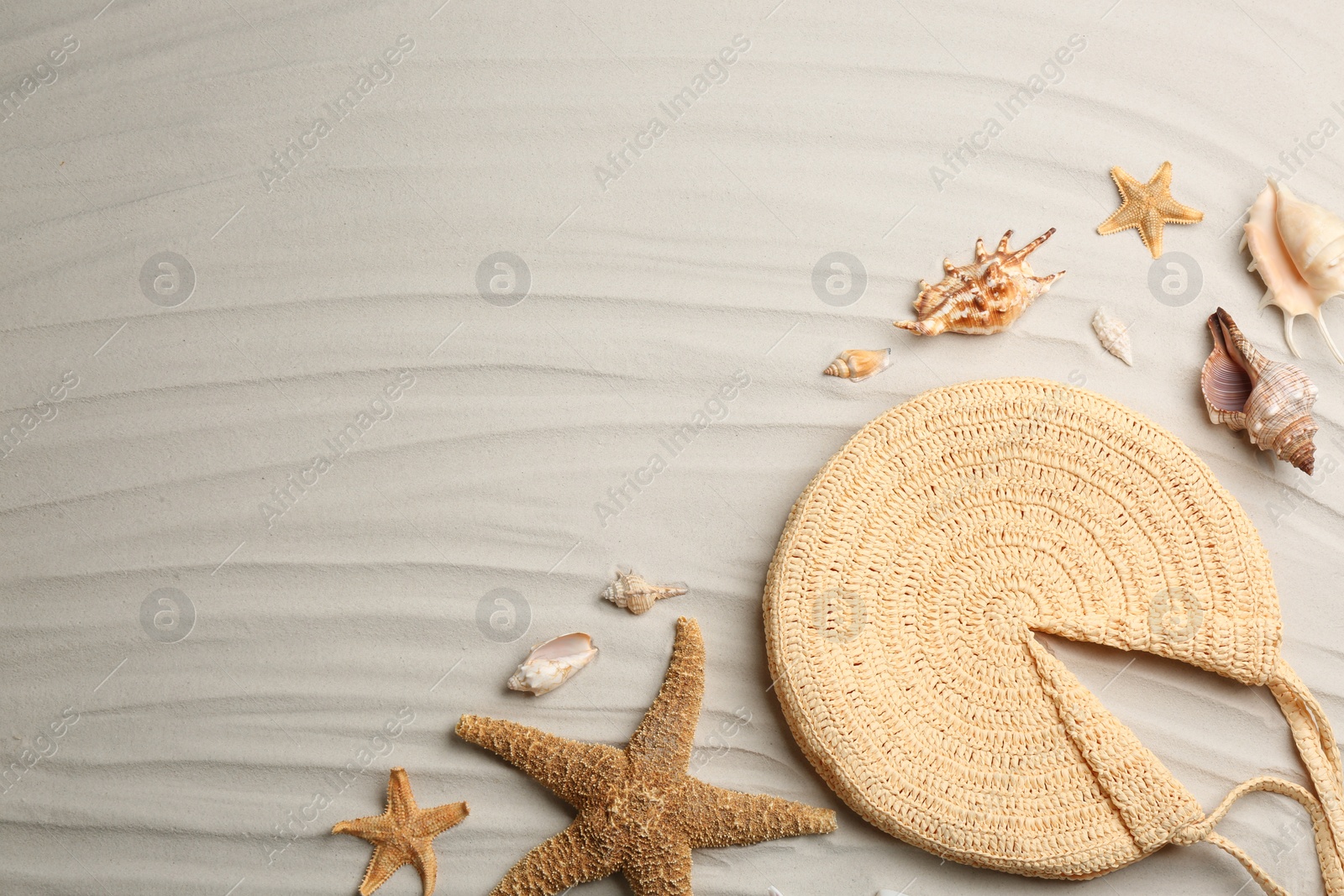 Photo of Flat lay composition with stylish knitted bag on sand, space for text. Beach accessory