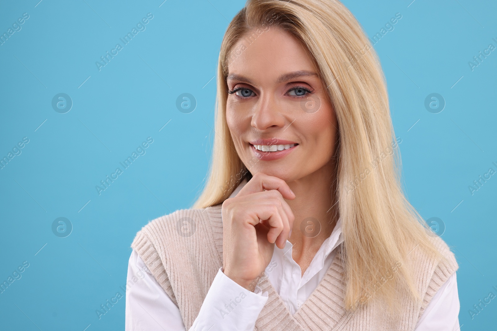 Photo of Portrait of smiling middle aged woman on light blue background. Space for text