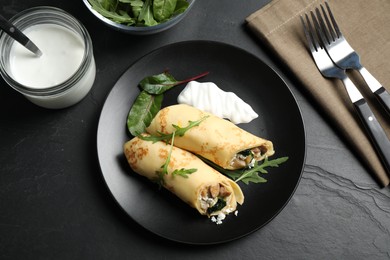 Photo of Delicious thin pancakes with chicken and mushrooms on black table, flat lay