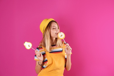 Young pretty woman with candies on colorful background