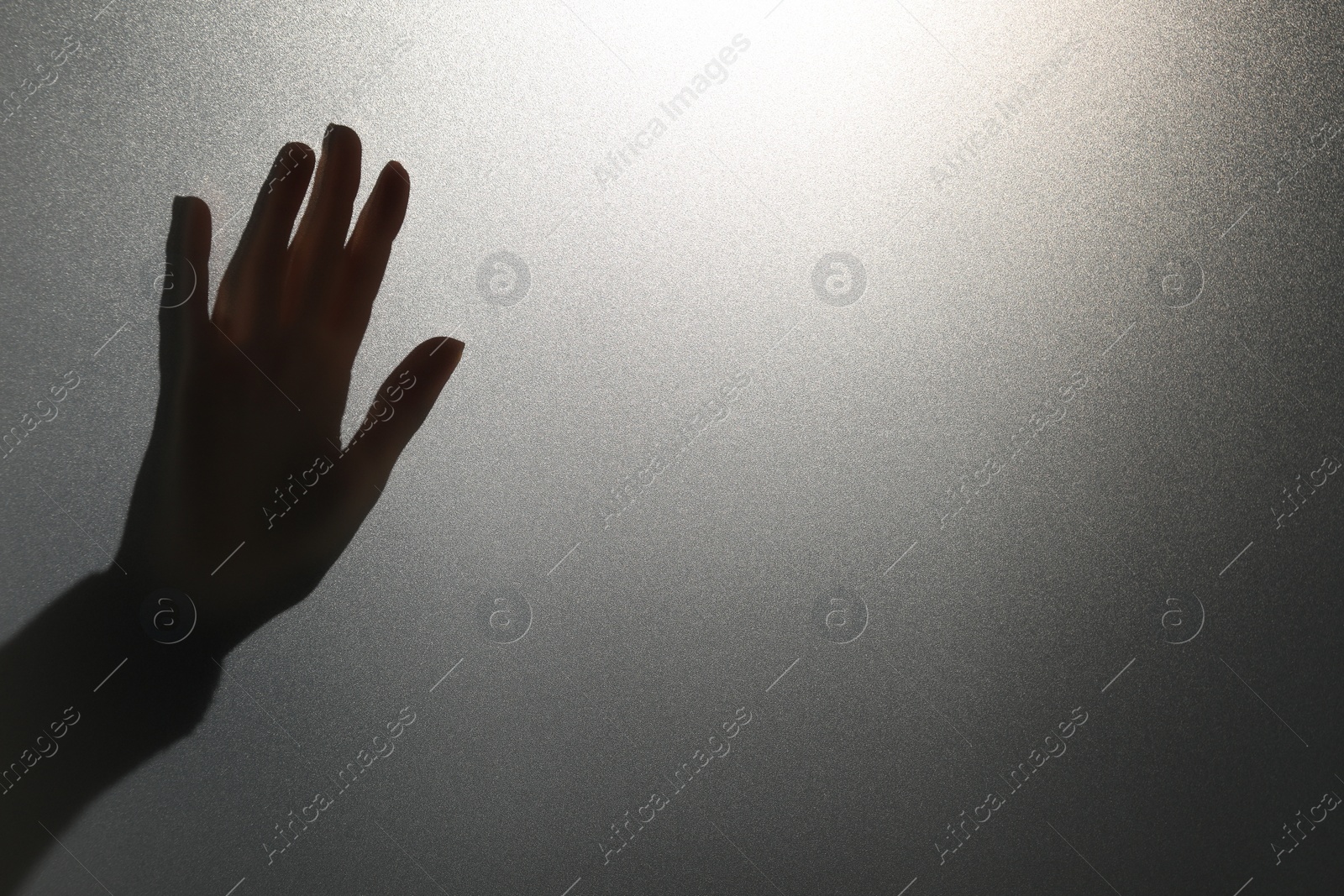 Photo of Silhouette of ghost behind glass against light grey background, closeup. Space for text
