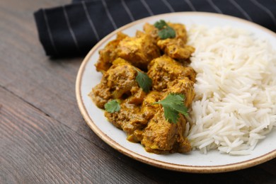 Photo of Delicious chicken curry with rice on wooden table, closeup