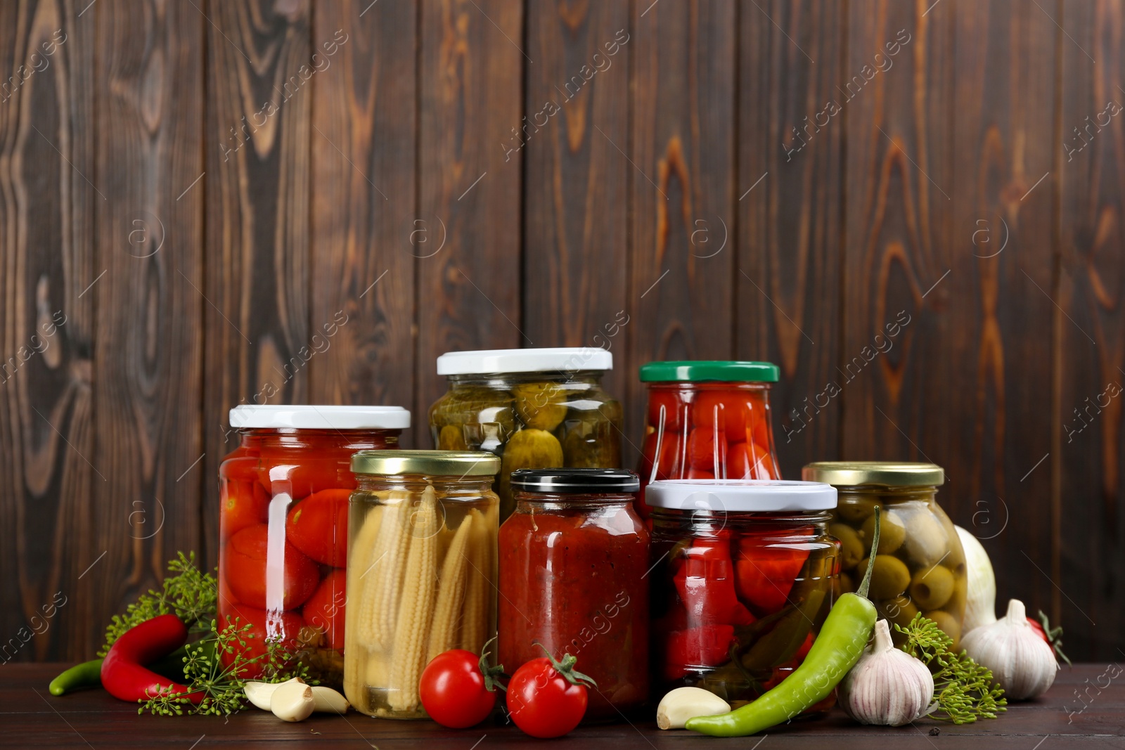 Photo of Jars of pickled vegetables on wooden table