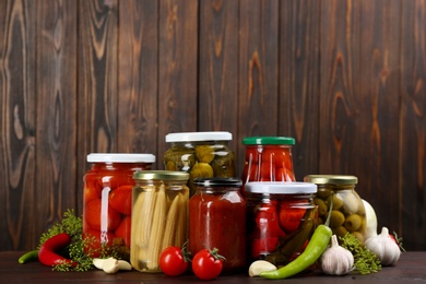 Jars of pickled vegetables on wooden table