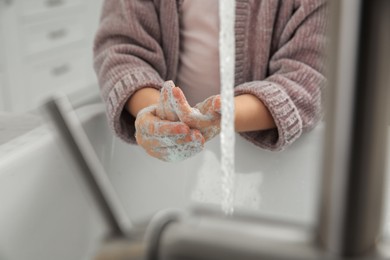 Little girl washing hands with liquid soap at home, closeup