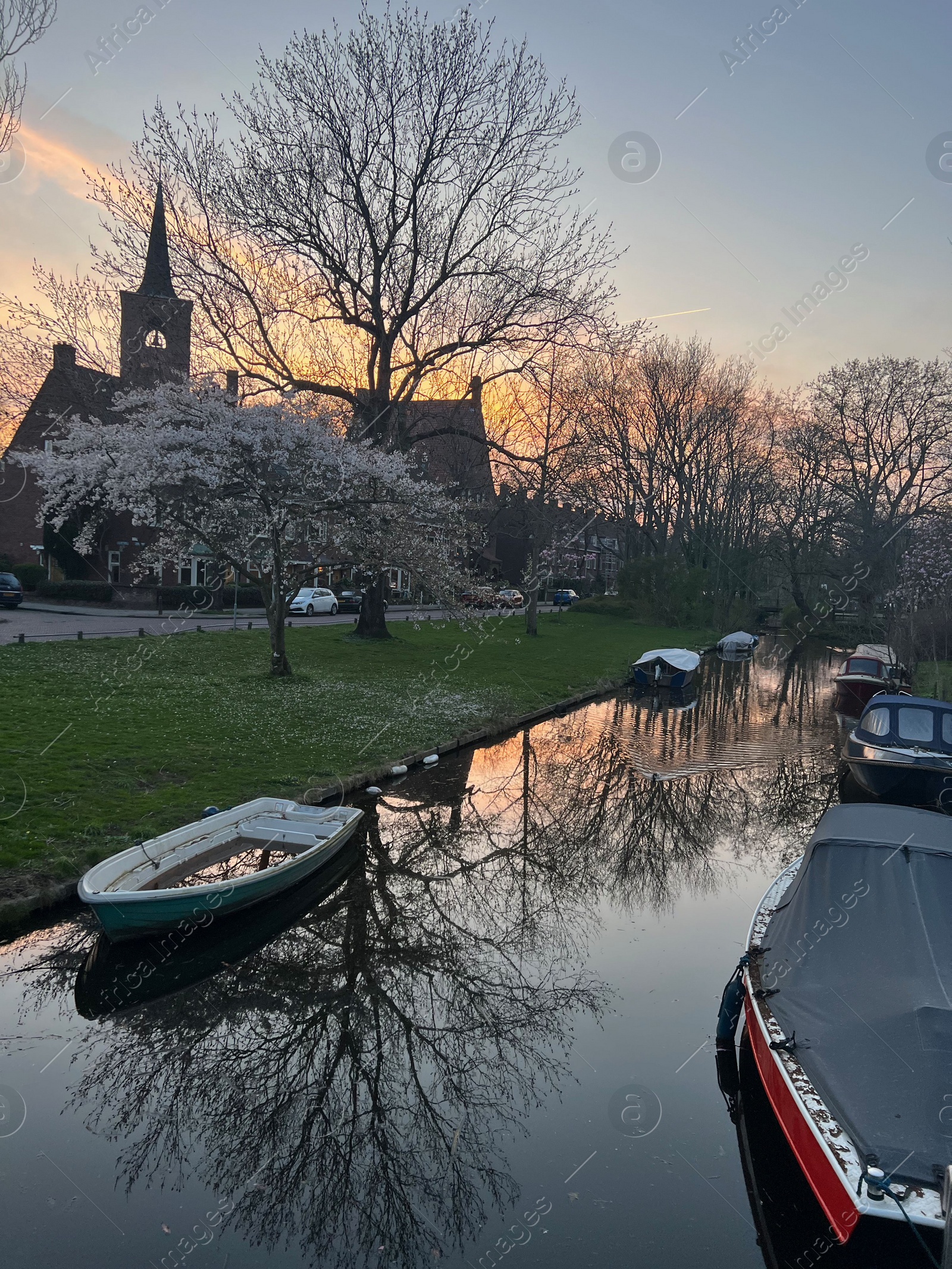 Photo of Canal with moored boats outdoors. Sky reflecting in water