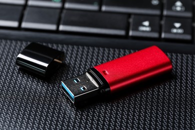Photo of Modern usb flash drive on laptop, closeup