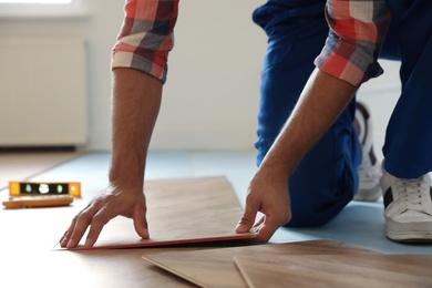 Professional worker installing new parquet flooring indoors, closeup