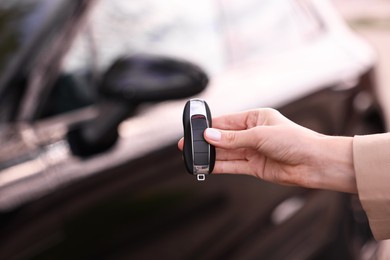 Woman holding car flip key near her vehicle outdoors, closeup