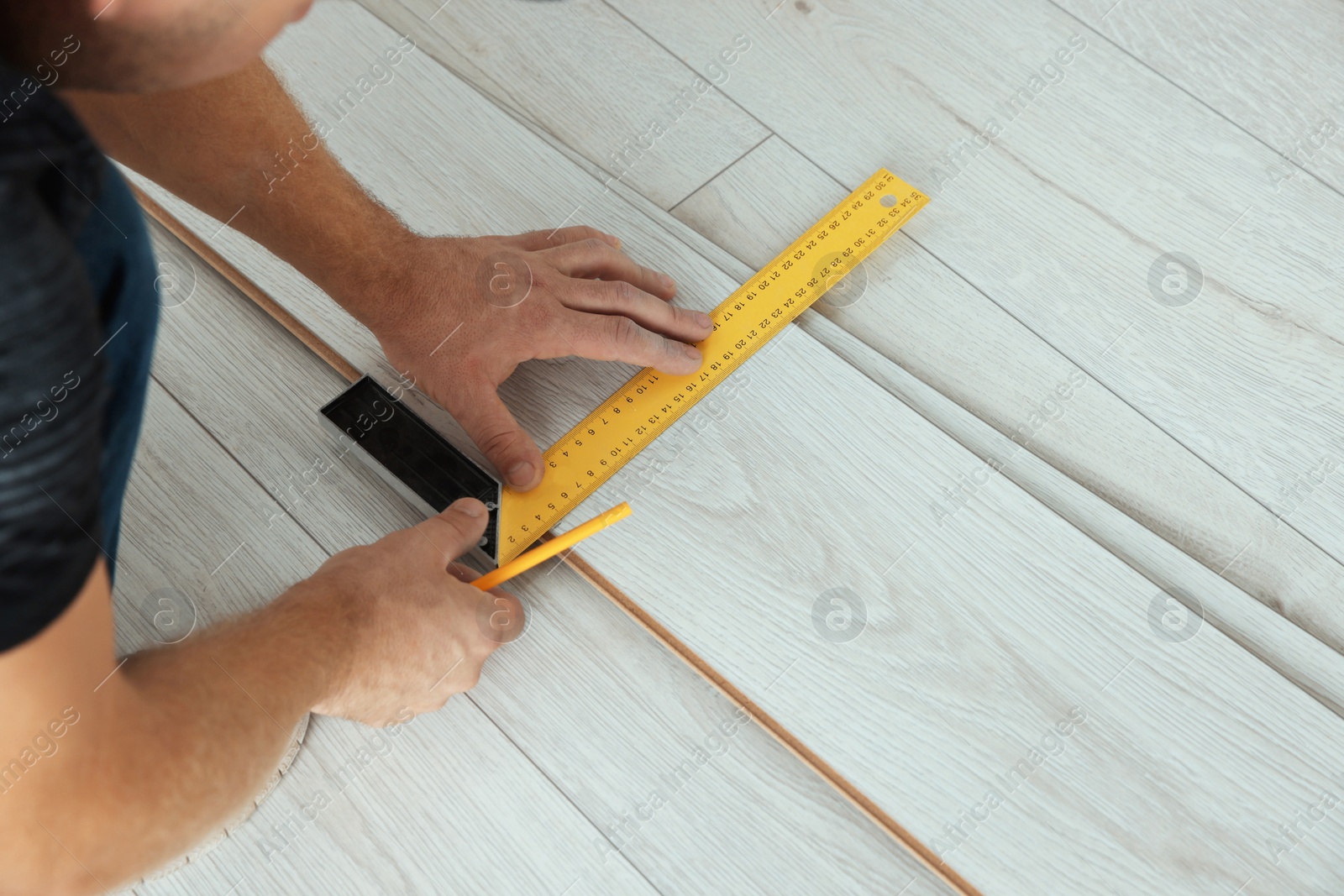 Photo of Worker installing new laminate flooring in room, closeup