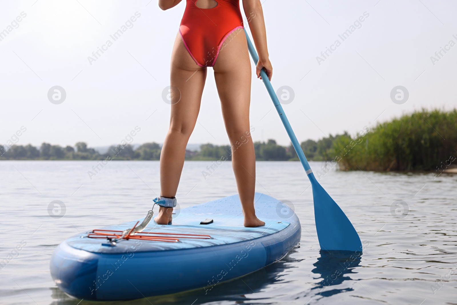 Photo of Woman paddle boarding on SUP board in sea, back view