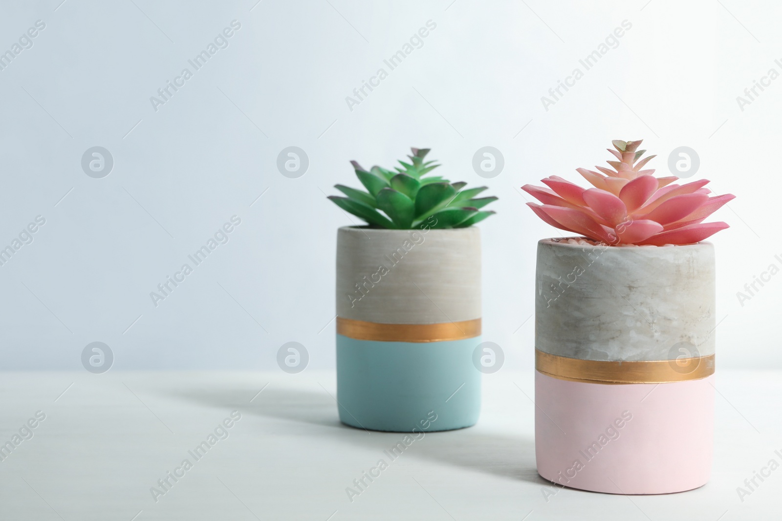 Photo of Artificial plants in flower pots on white wooden table. Space for text