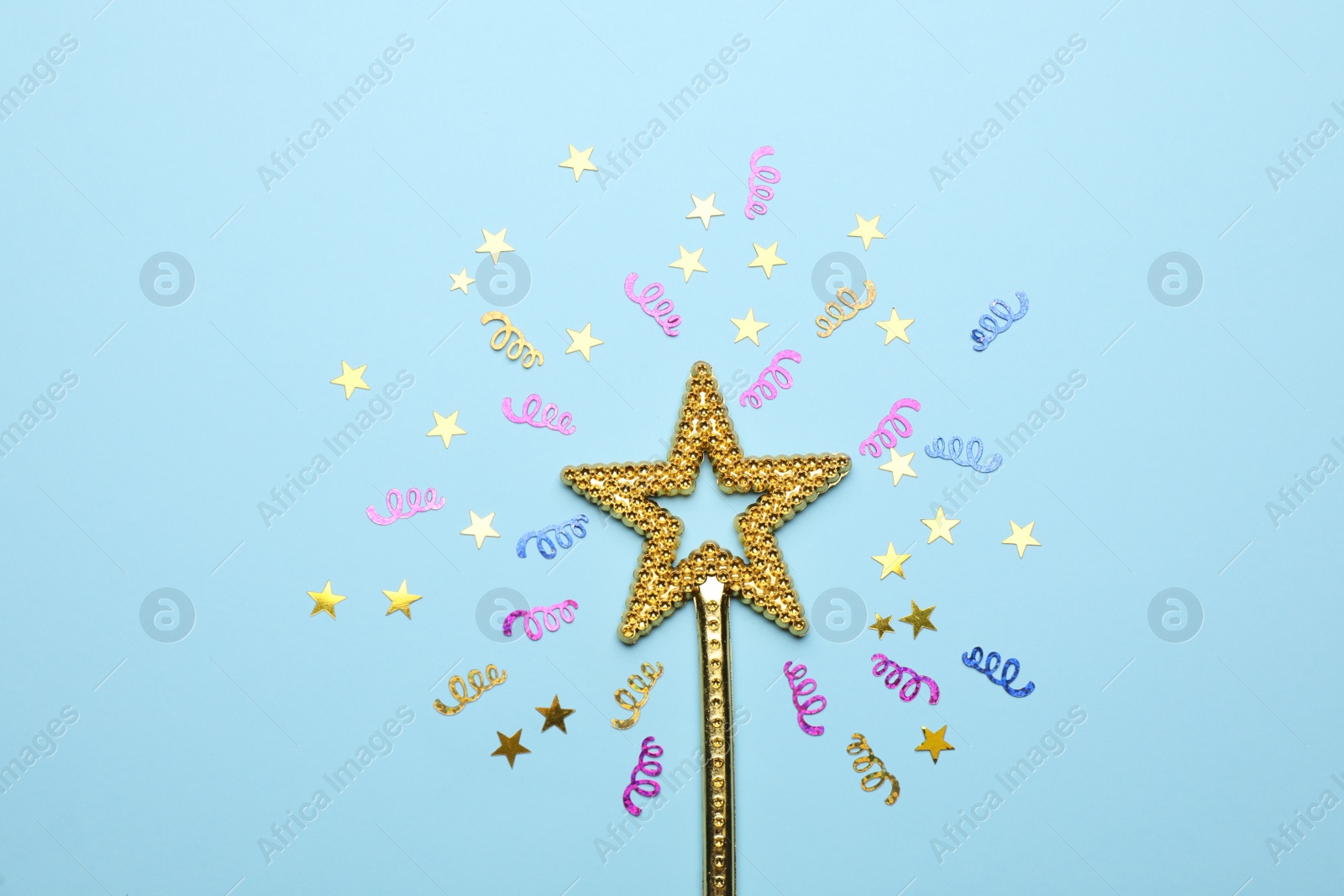 Photo of Beautiful golden magic wand and confetti on light blue background, flat lay